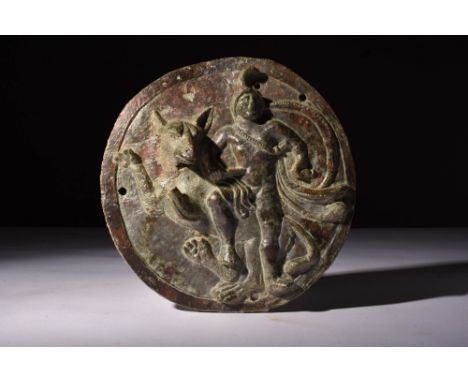 Ca. AD 200 - 300.A large cast bronze disc phalera with a high-relief image of Mithras, standing with a dog. Mithras is known 