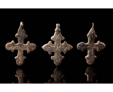 Ca. AD 900 - 1200.A collection of three Byzantine silver cross pendants with domes on their arms. They have a round hoop to s
