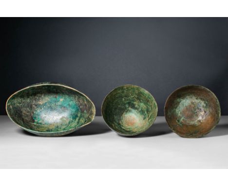 Ca. 500 - 300 BC.A collection of Etruscan, cast-bronze bowls. The first bowl, on the left, has an ovoid shape, deformed with 