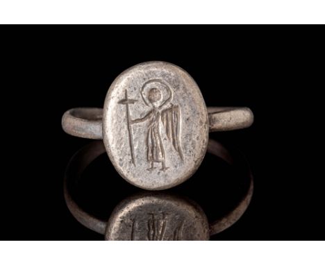 Ca. AD 500 - 700.A Byzantine silver ring composed of a round hoop connected to a round bezel. The ring is engraved with a sta