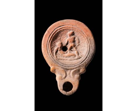 Ca. AD 100 - 300. A Roman terracotta round oil lamp with a recessed central disc and double volutes. The decorated disc is ad
