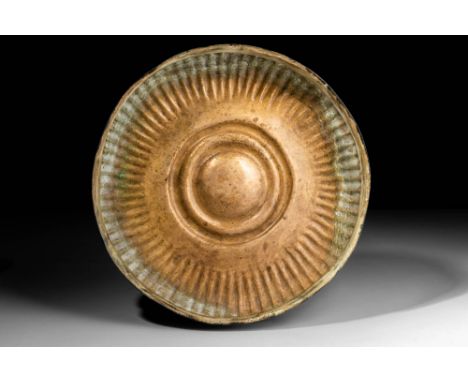 Ca. 500 - 330 BC .A bronze phiale with a globular shape. Its centre displays concentric rings and an exterior wall of ribbed 