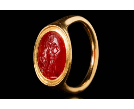 Ca. AD 100 - 300.A Roman red carnelian intaglio depicting the god Asclepius, standing in a relaxed position with his hand on 