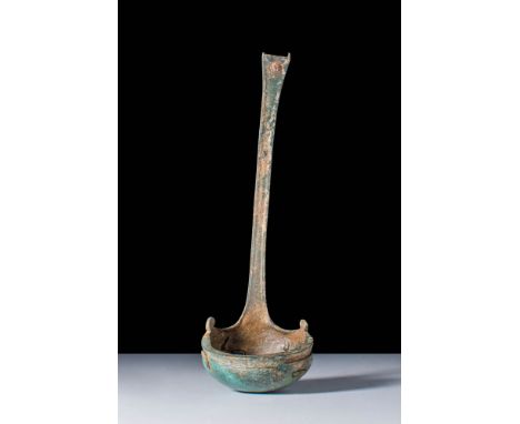 Ca. AD 100 - 300.A Roman bronze ladle with a deep round body and a long handle. The body has a moulded decoration on the rim 