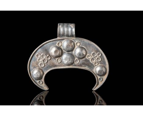 Ca. AD 800 - 1100.A Viking silver pendant shaped like a crescent, with four small raised circles in the centre and two more o