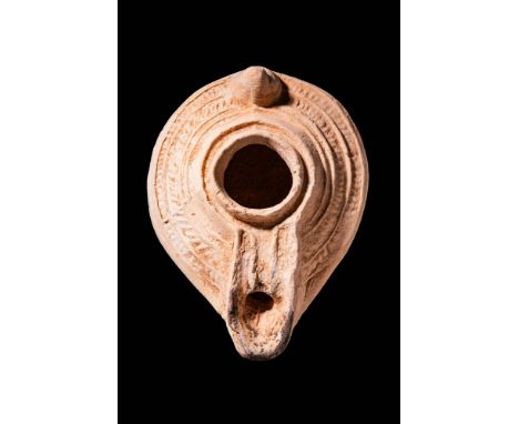 Ca. AD 400 - 500. A Levantine oil lamp with a large hole adorned with a moulded geometric decoration. It has a small vertical