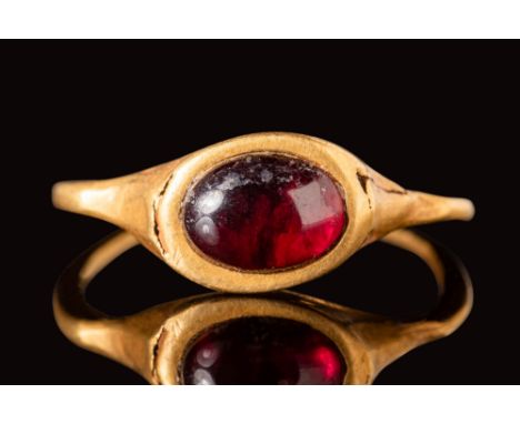 Ca. AD 400 - 600.A Merovingian gold ring with an angular hoop and a high oval bezel, securing a red oval garnet cabochon.Size
