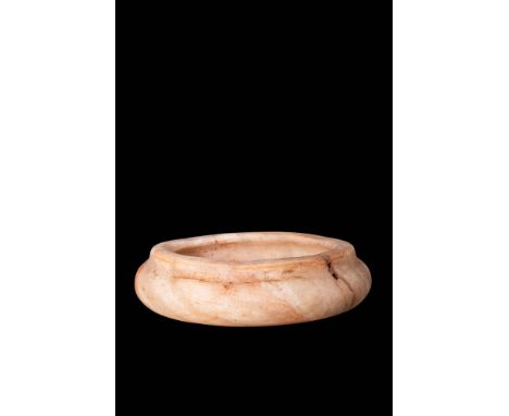 Old Kingdom, Ca. 2750 - 2649 BC.An Egyptian shallow bowl carved from creamy alabaster. It has a flat base, rounded body, curv