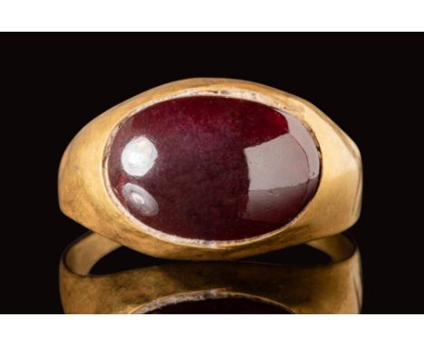 Ca. AD 400 - 600.A Merovingian gold ring with an oval bezel, securing a large oval red garnet cabochon.Size: D:18.34mm / US: 