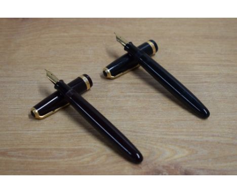 Two Parker Duofold button fill fountain pens one in dark brown the other black with Duofold broad cap band. Brown having Park