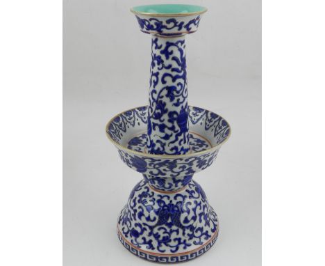 A Chinese blue and white porcelain candlestick, with flared drip tray raised on a bell shaped base, decorated with scrolling 