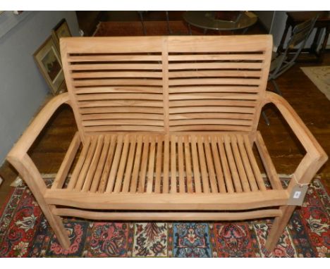 A teak garden bench of modern slatted form on square legs W 120 cms