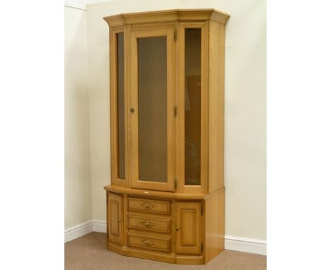 Light oak illuminated display cabinet enclosed by single glazed door, three drawers and cupboard either side below, W106cm, H