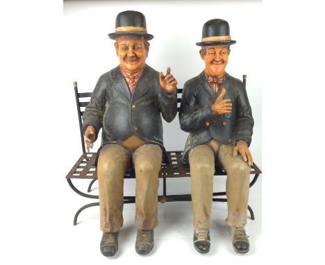 Stan Laurel and Oliver Hardy resin models sat on a metal  garden bench, 57cm wide, 40cm deep and 60cm high approximatelyHardy