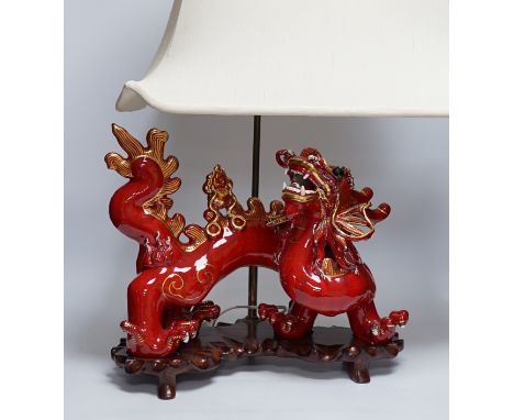 A modern Chinese red and gilt glazed ceramic 'dragon' table lamp on carved wood stand with shade, total height 68cm