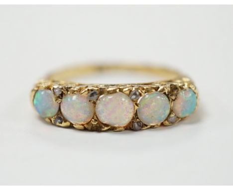 A late Victorian yellow metal and white opal five stone ring with diamond chip set spacers, size M