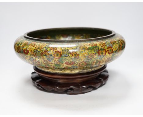 A Chinese circular cloisonné enamel  bowl decorated with multi-coloured flowerheads on wooden stand, 30cm diameter