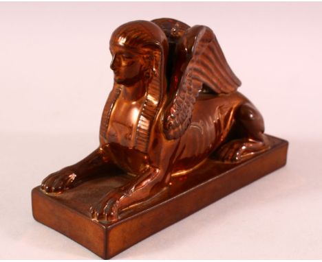 AN UNUSUAL COPPER LUSTRE DECORATED POTTERY MODEL OF SPHINX, impressed mark to base Wedgwood, 17cm long.