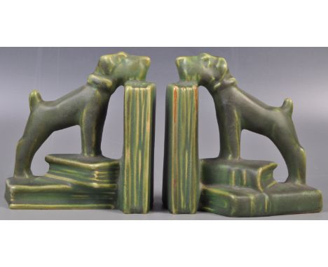A pair of early 20th Art Deco retro vintage ceramic bookends in the form of a dog climbing on a stack of books. In green pain