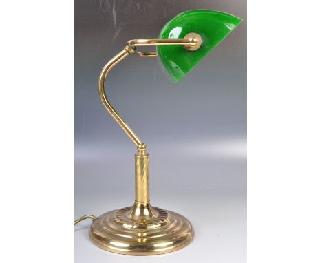 A 20th Century vintage bankers desk / table lamp light of brass construction having an adjustable green glass shade supported