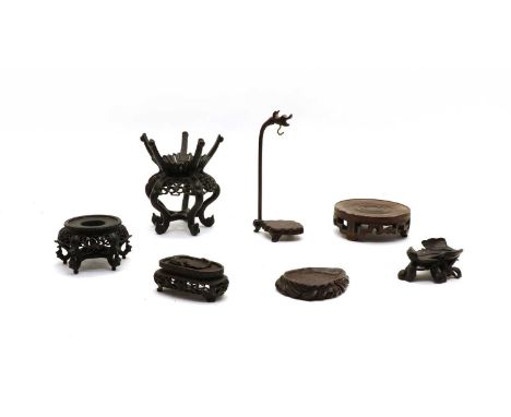 Seven Chinese wood stands, 19th-20th century, including one on S-shaped legs and pierced scroll aprons, with five prongs, 14c