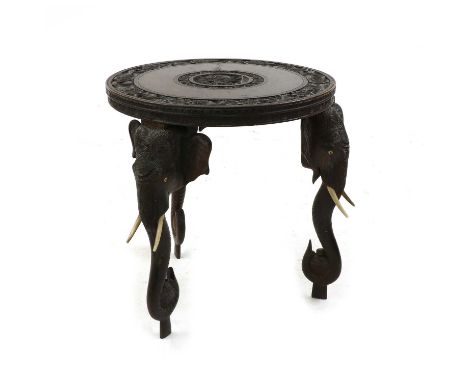 An Indian hardwood occasional table, early 20th century, the circular top carved with a central roundel depicting figures and