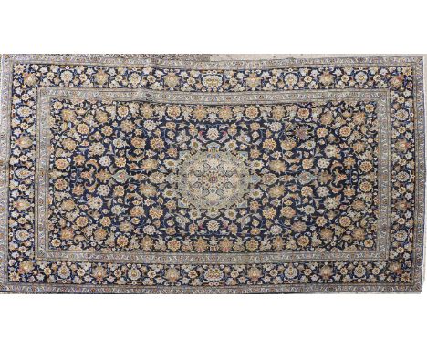 A Persian Kashan carpet, 20th century, the field woven with a central scrolling medallion, within floral and foliate motifs a