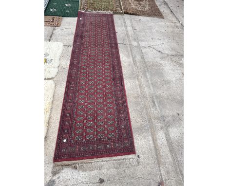 A RED PATTERNED FRINGED CARPET RUNNER