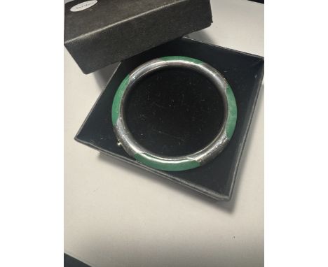 AN APPLE JADE AND CHASED SILVER BANGLE, 2.5 INCHES IN A PRESENTATION BOX