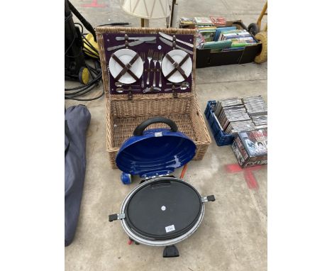 A WICKER PICNINC HAMPER WITH PICNIC ITEMS AND A GAS CAMPING STOVE