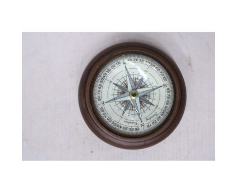A NAUTICAL DESK COMPASS IN A WOODEN SURROUND