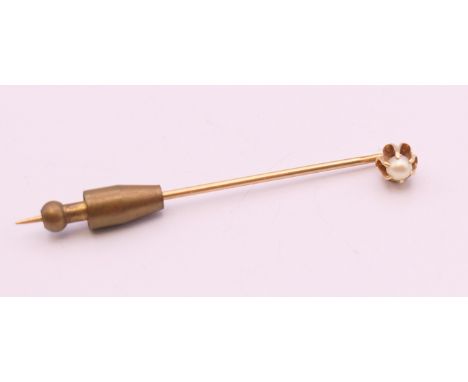 An unmarked 9 ct gold stick pin mounted with a single pearl.  5.5 cm long. 