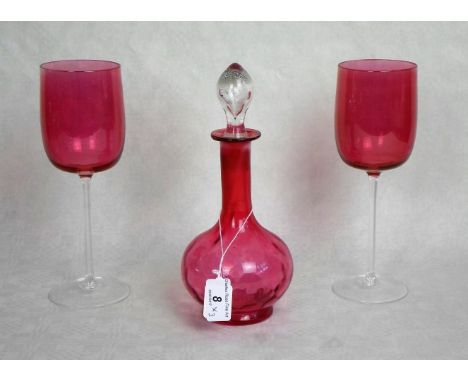 A cranberry glass decanter and stopper, together with a pair of cranberry and clear glass wine glasses.