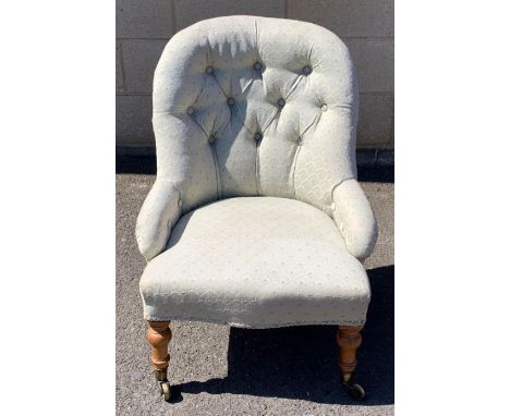 A Victorian button back  armchair, with a spoon shaped back, standing on walnut legs 