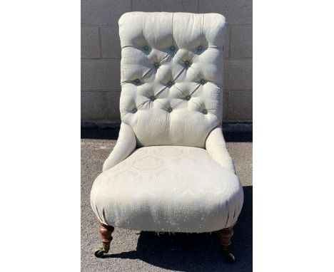A Victorian button back chair, standing on mahogany legs and brass casters 