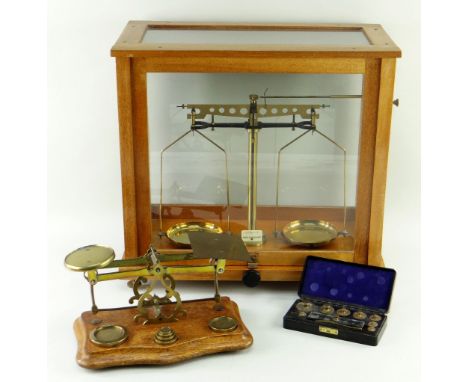 TWO BRASS SCALES, comprising wood cased scientific scale, brass and oak postal scale with set of weights and a Bakelite boxed