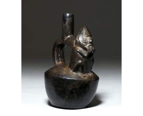 Pre-Columbian, North Coast Peru, Chimu, ca. 1000 to 1400 CE. A handsome burnished blackware mold-made stirrup vessel adorned 