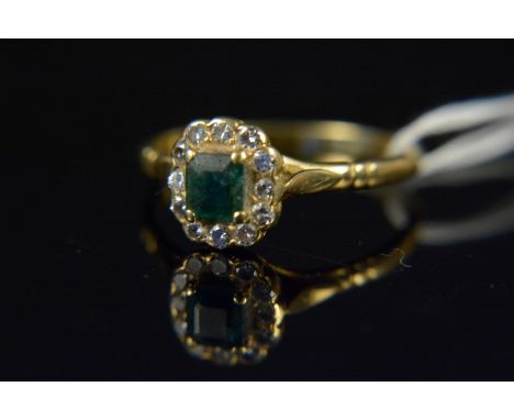 An 18ct gold emerald and diamond cluster ring, the square emerald in raised four claw setting with diamond surround, size P 1