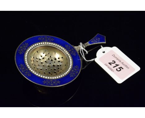 A silver tea strainer with blue and white enamelled decoration (small losses to enamel)
