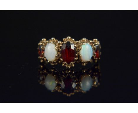 A gold garnet and opal five stone ring, bead work setting to stones and engraved shoulders