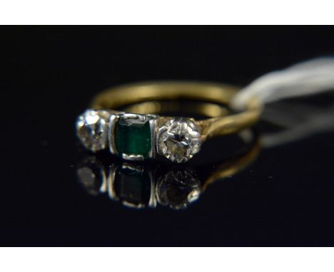 An 18ct platinum set emerald and diamond three stone ring, the centre squared emerald flanked by a diamond either side (heavy