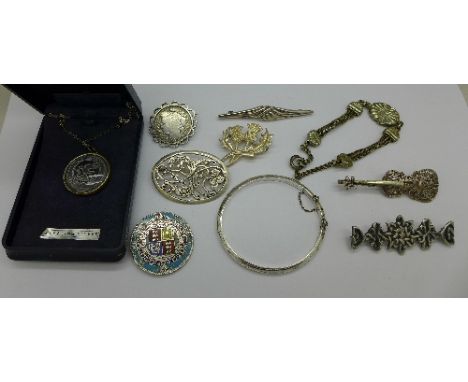Silver jewellery including brooches and a bangle, enamelled coin brooch lacking pin