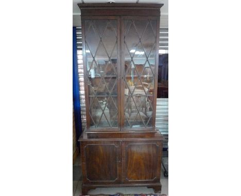An early 19th century mahogany bookcase, with unusually tall astragal diamond paned glazed doors enclosing shelves, the base 