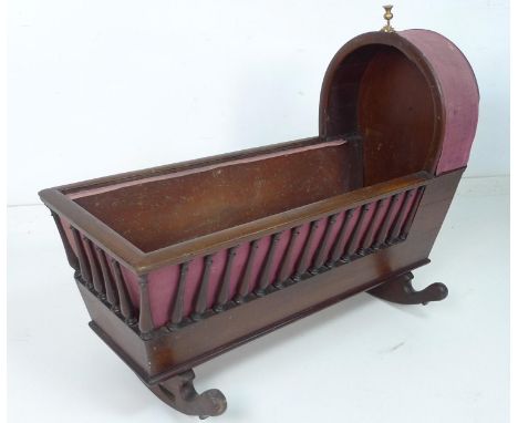 A Victorian mahogany rocking crib, with turned spindle sides, hood to one end with brass thistle finial, internally fitted wi