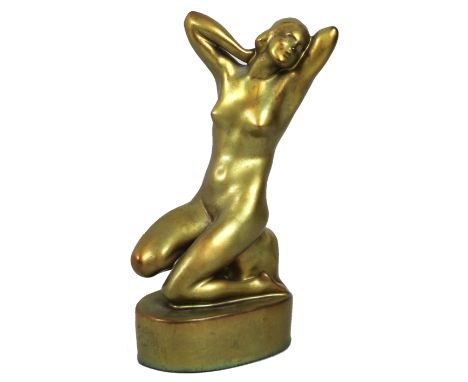 An Art Deco Zsolnay Pecs figurine, modelled as a female nude in kneeling pose with her hand clasped behind her head, on an ov