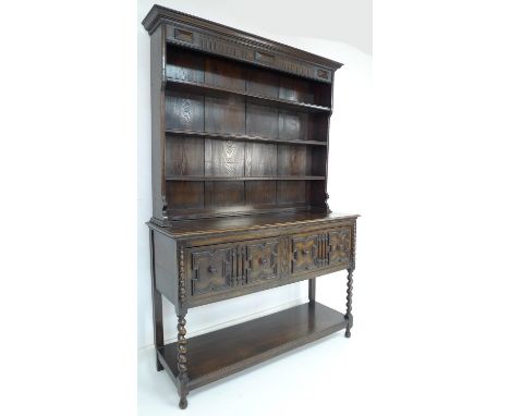 A mid 20th century oak dresser with two shelf plate rack, two panelled doors with an undertier united by barley twist support