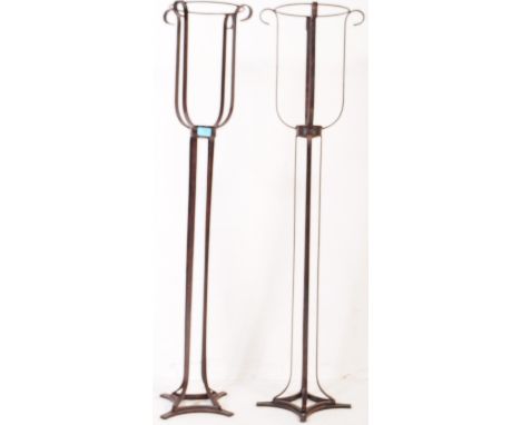 A pair of contemporary metal floor standing tea light / candle holders. The lights standing on splayed feet, with a bent meta