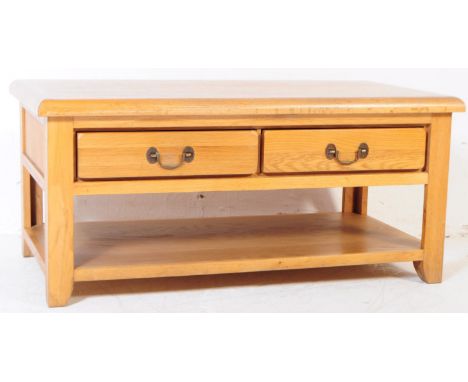 A contemporary oak coffee table with twin sliding drawers. Handles either side, chamfered edge top with lower shelf / magazin