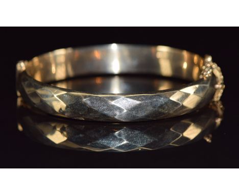 A 9ct gold bangle with faceted design, 13g