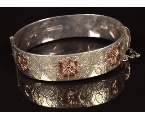 A hallmarked silver bangle with gold floral decoration&nbsp;